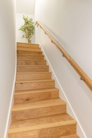 A wooden staircase with a handrail and a potted plant at the top.