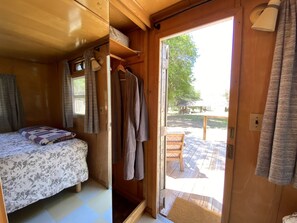 Acogedora habitación tipo cabaña con una cama, una mesita y una puerta que da a una terraza exterior.