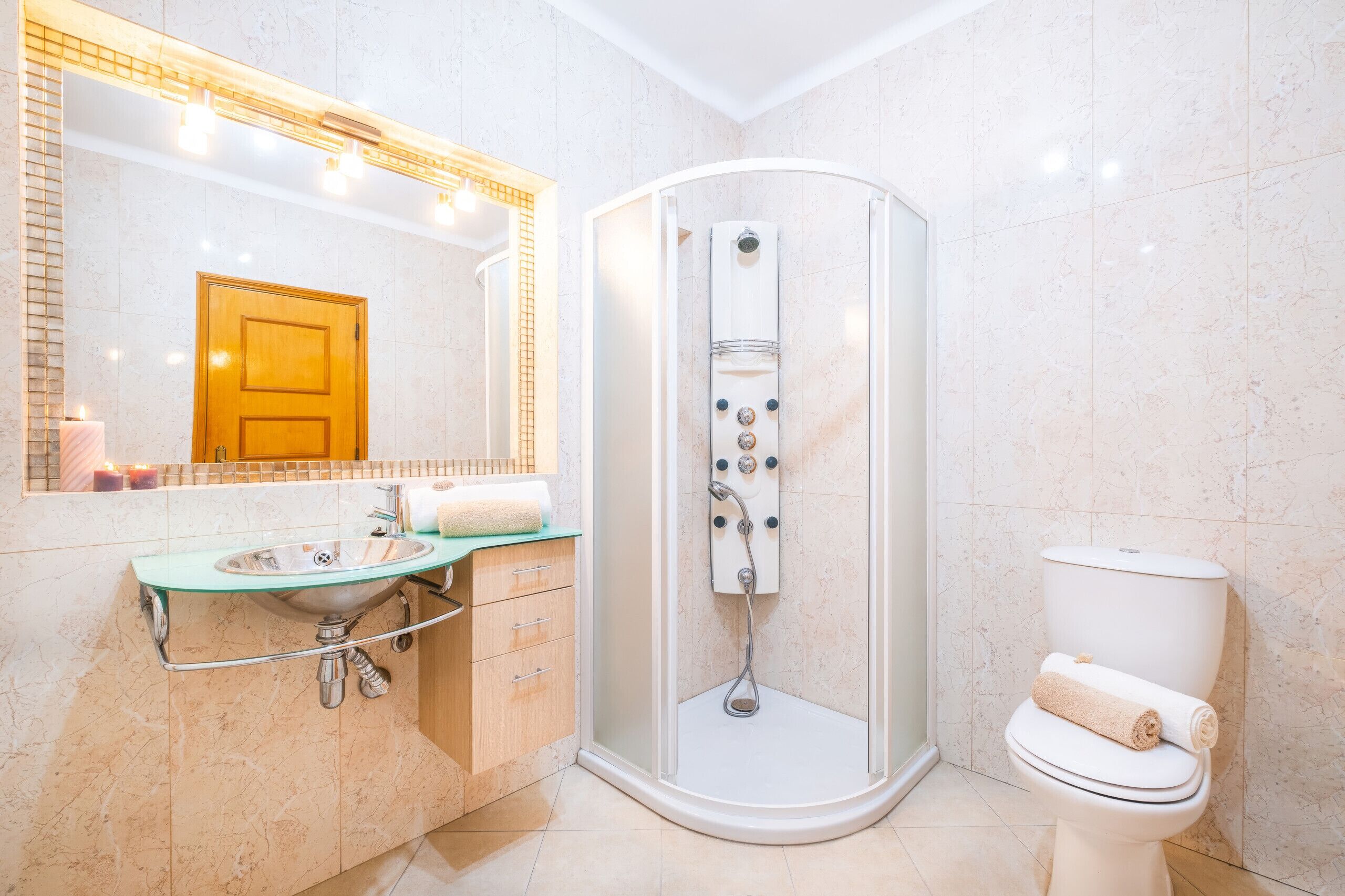 A modern bathroom with a glass-enclosed shower, a sink with a marble countertop, and a toilet.