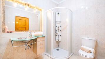 A modern bathroom with a glass-enclosed shower, a sink with a marble countertop, and a toilet.