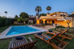 Une piscine avec des chaises longues et un espace patio.