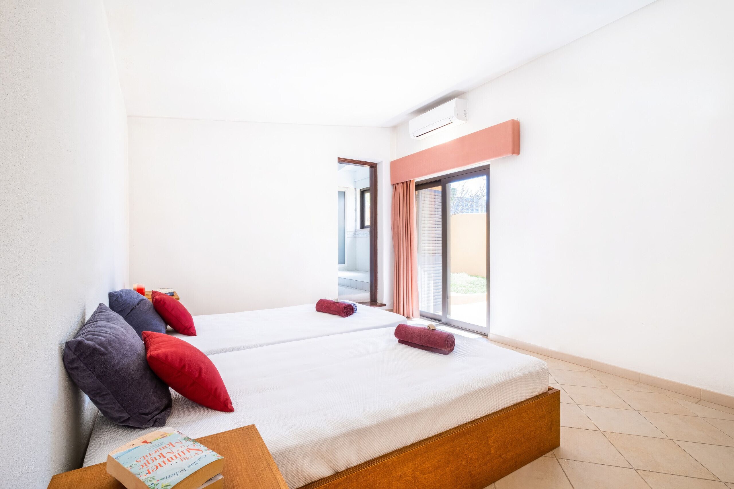 Une chambre d’hôtel avec un grand lit, une tête de lit en bois, une fenêtre avec des rideaux et une vue sur l’extérieur.