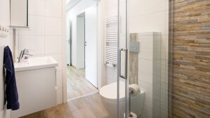 Une salle de bain moderne avec une douche à parois de verre, un lavabo blanc et des toilettes.