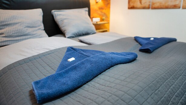 Un lit bien fait, avec une couverture matelassée, des oreillers et une serviette pliée.