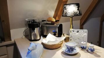 Eine Küchenarbeitsplatte mit Kaffeemaschine, Toaster, Brot, einer Lampe, einem dekorativen Teller, einer Tasse und Salzstreuern.