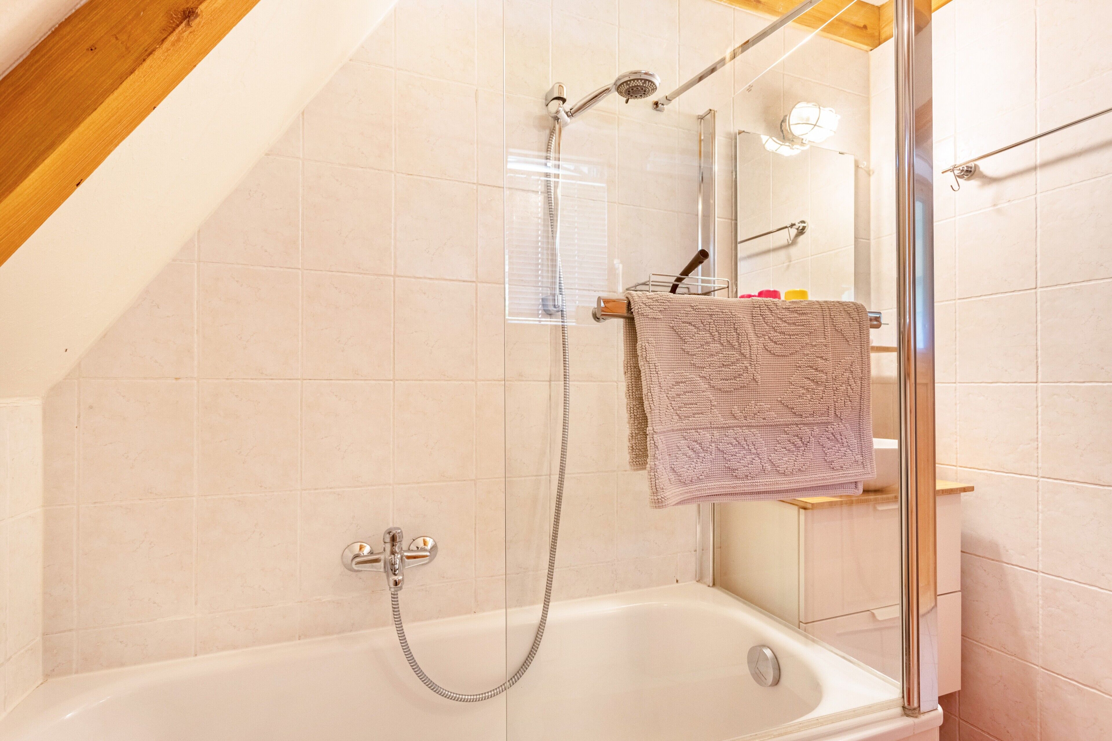 A shower area with a glass door, a bathtub, and a towel rack with a towel.