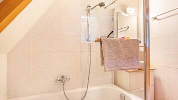 A shower area with a glass door, a bathtub, and a towel rack with a towel.