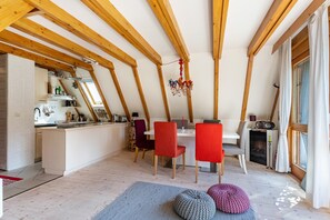 Een eetgedeelte met een hoge plafond, houten balken en uitzicht op de keuken.