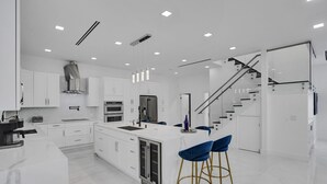 A modern kitchen with white cabinetry, a central island, and a stainless steel refrigerator. - 4 Bedroom Designer Home Next to Shul and Community Pool (Fort Lauderdale)