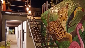 Un escalier orné d’une fresque représentant un léopard et un flamant rose, menant à un espace abrité où sont disposées des plantes en pot.