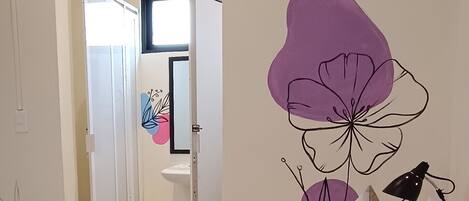 Un dormitorio con una colcha naranja, un cojín floral y un mural en la pared.