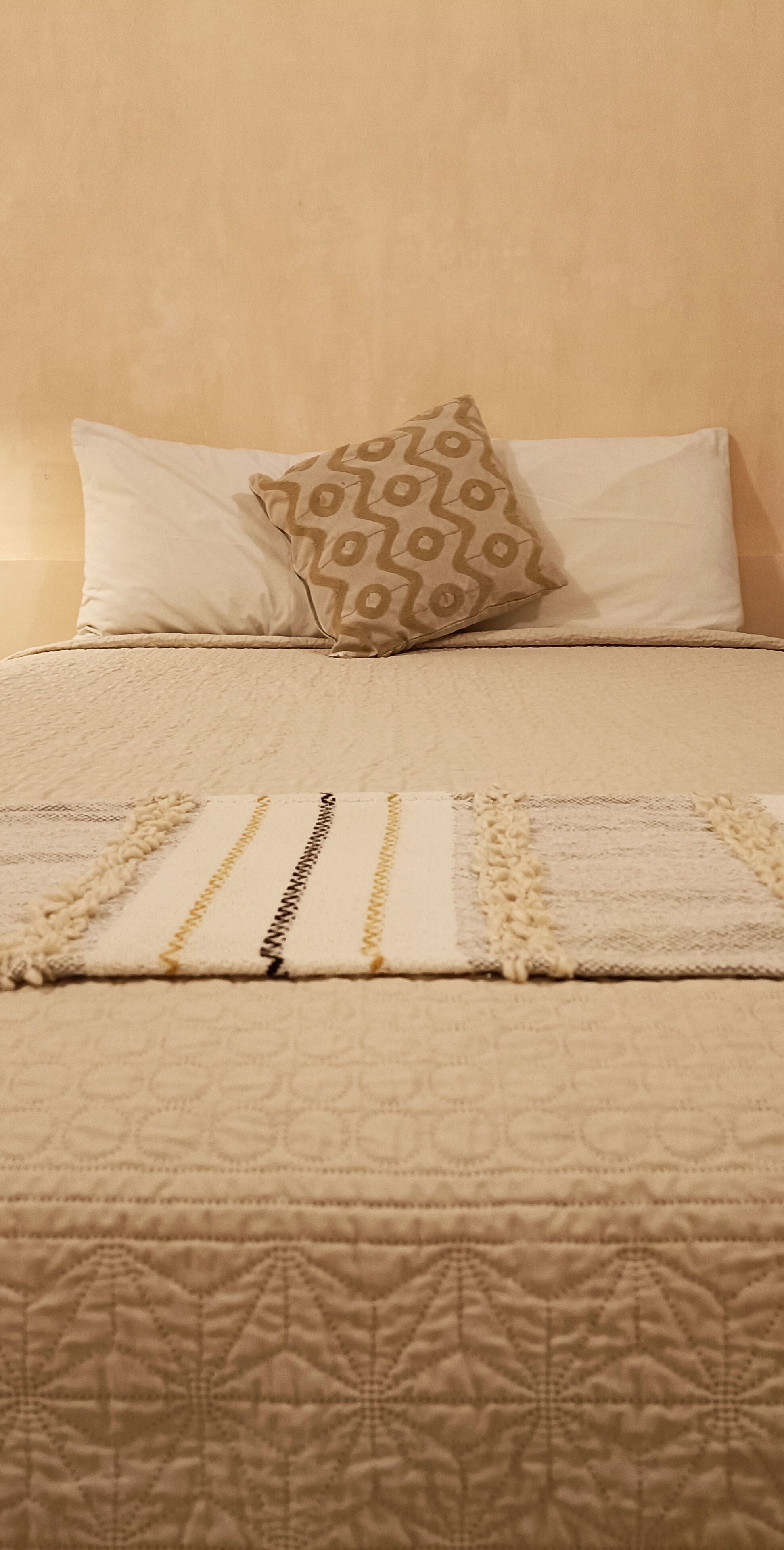 A bed with a patterned quilt, two pillows, and a decorative throw.