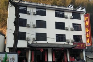 A multi-story building with a traditional architectural style, featuring a tiled roof and a red signboard.