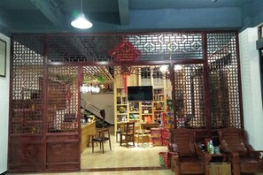 A traditional room with a wooden partition, a television, a bookshelf, and seating area. - Yiyuanchun Shanju Hotel (Huangshan City)