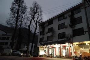 A multi-story building with a ground-floor commercial space, including a brightly lit entrance and signage.