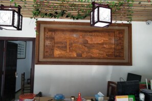 A room with a traditional wooden door, a framed artwork on the wall, and a desk with various items. - Yiyuanchun Shanju Hotel (Huangshan City)