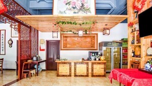 Un interior tradicional con un mostrador de recepción, muebles de madera y un mantel rojo.