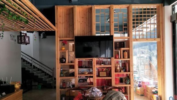 Una habitación con televisión, estantes de madera, una escalera y vistas al exterior.