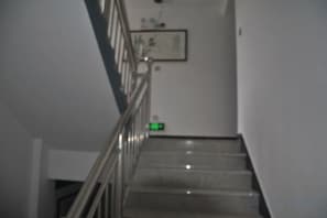 A staircase with a handrail and a green exit sign on the wall. - Yiyuanchun Shanju Hotel (Huangshan City)