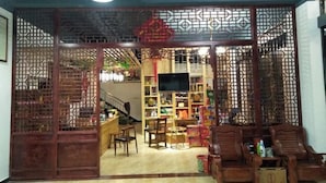 Habitación de estilo chino tradicional con un separador de madera, un televisor y varios objetos en estantes.