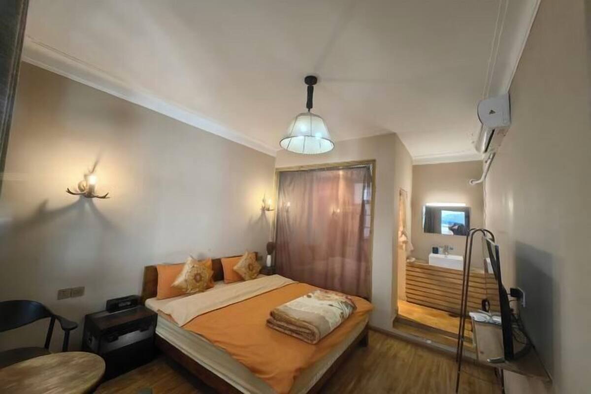 Une chambre à coucher avec un lit, une table de chevet, une lampe et une vue sur la salle de bain.