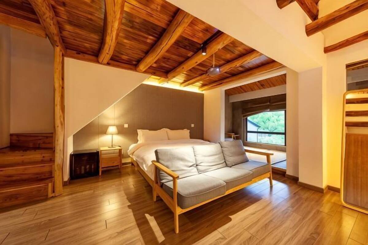 Une chambre à coucher avec un plafond en bois, un lit, une table de chevet, une fenêtre et une porte.