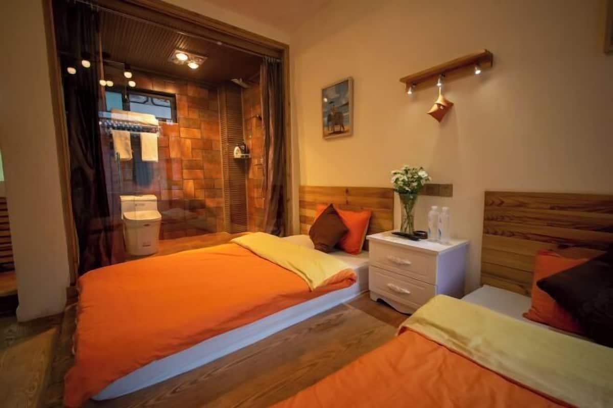 Une chambre avec un grand lit, une table de chevet ornée d’un vase et une tête de lit en bois.