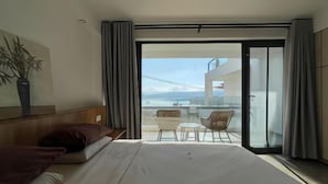 A hotel room with a bed, a small table, a chair, and a balcony with a view of the city. - Hmyway (Dali City)