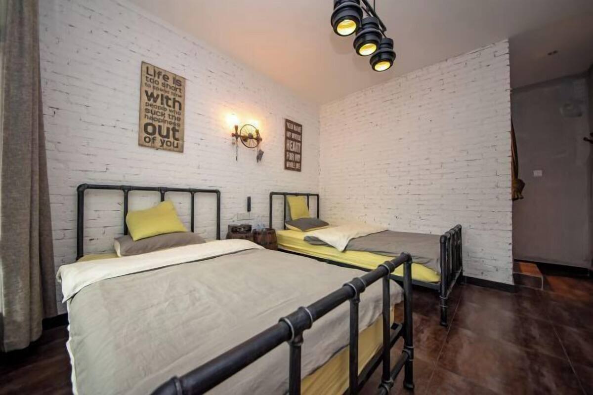 Une chambre avec deux lits, un mur en briques et un luminaire au plafond.