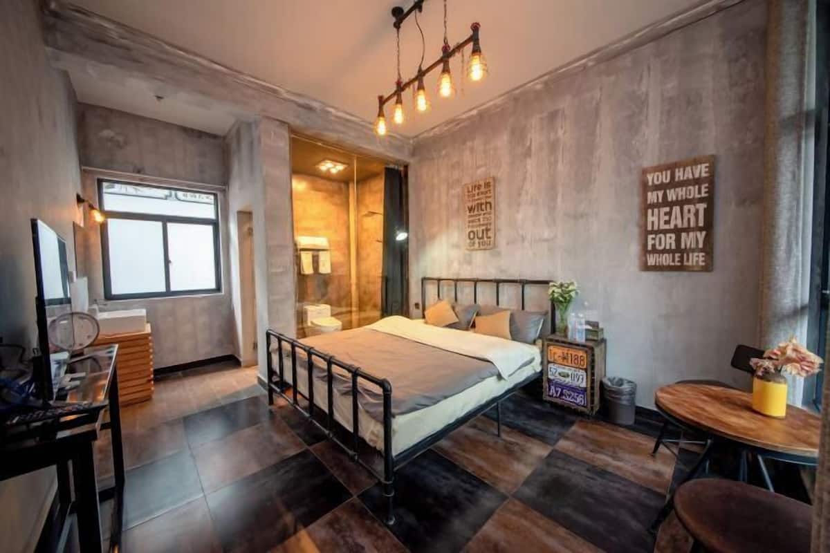 Une chambre moderne avec un lit, un bureau, une chaise et une petite table. Il y a deux panneaux accrochés au mur, l’un avec une citation motivante et l’autre avec un numéro d’immatriculation.