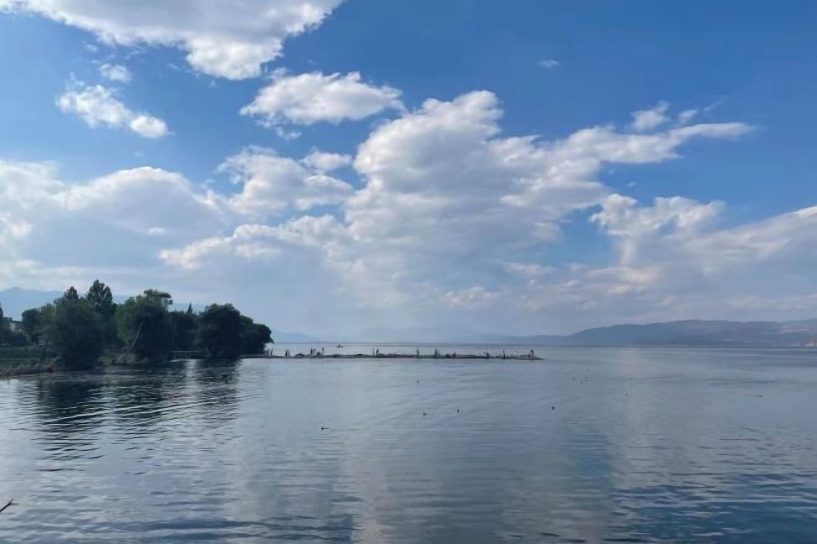 Un lago tranquilo con cielo despejado y una orilla lejana.