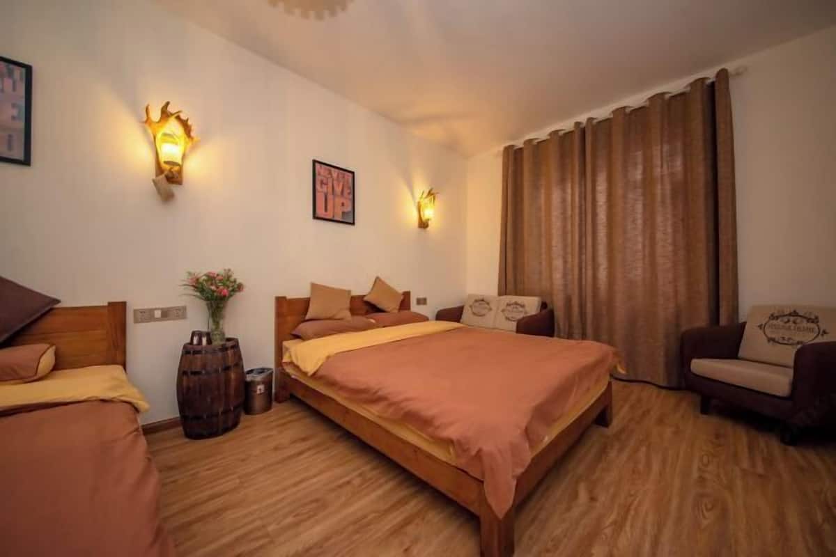 Une chambre avec un lit en bois, deux lampes fixées au mur, un tableau encadré, un vase avec des fleurs et un rideau marron.