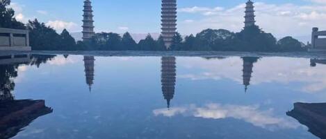 A reflection of pagodas on a calm water surface, surrounded by trees and buildings.