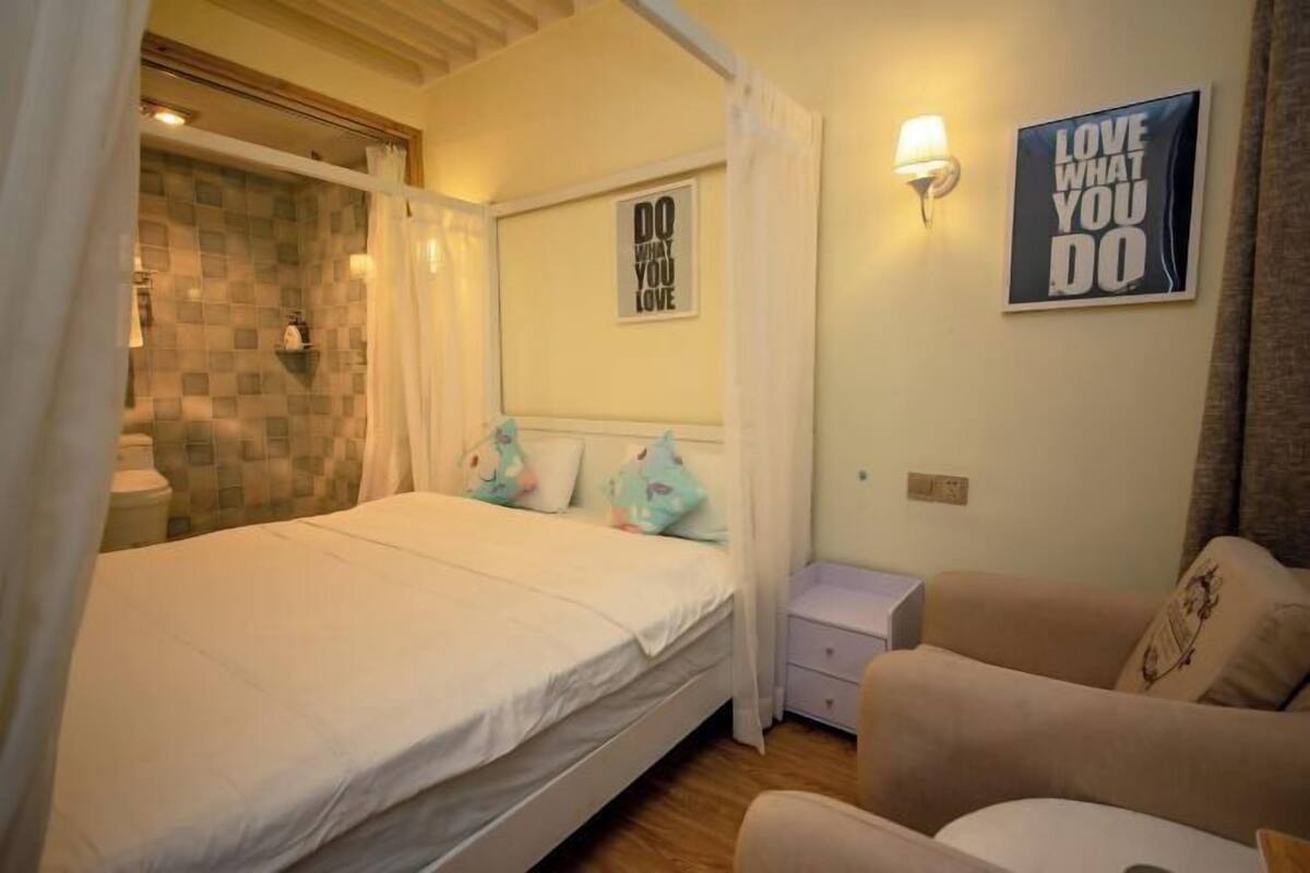 Une chambre à coucher comprenant un lit, une table de chevet, une chaise, une lampe fixée au mur et une affiche motivante.