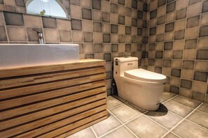 A bathroom with a wooden vanity, a white toilet, and a tiled wall.