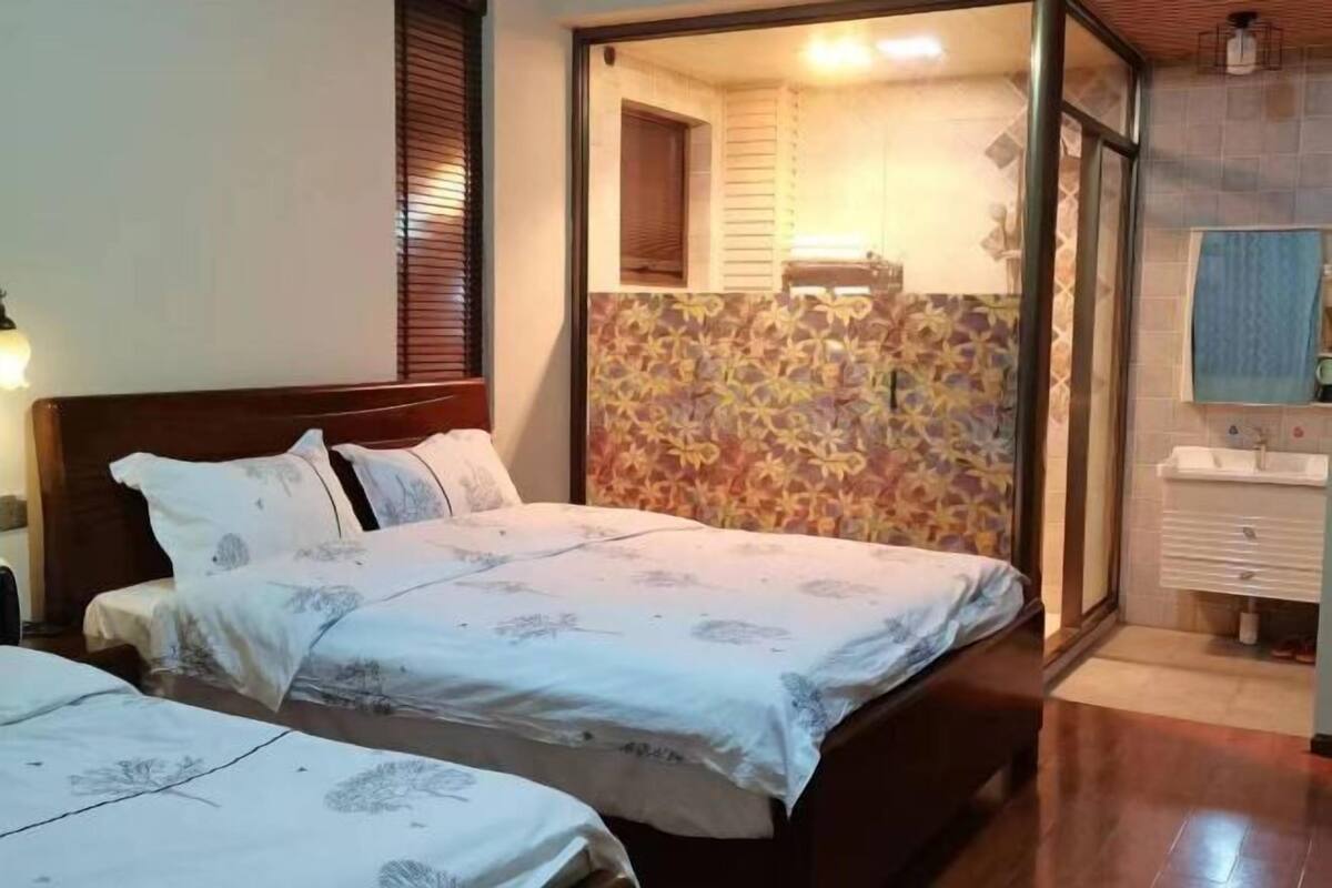 Une chambre d’hôtel avec deux lits, une salle de bain avec douche et un mur décoré d’un motif.