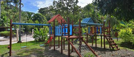 A playground with climbing structures, swings, and a netted area.
