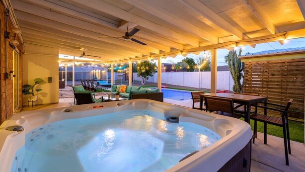 Ein Whirlpool in einem überdachten Außenbereich mit Sitzgelegenheiten und einem Pool im Hintergrund.