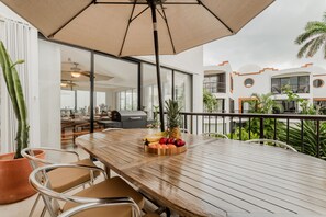 Enjoy al fresco dining with a view of the city from this outdoor dining area, featuring a table and chairs under a shaded umbrella.