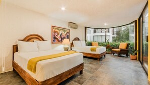 A hotel room with two beds, a large window, a balcony, and a view of greenery. - Zoque's Mexican Villa (Cancún)