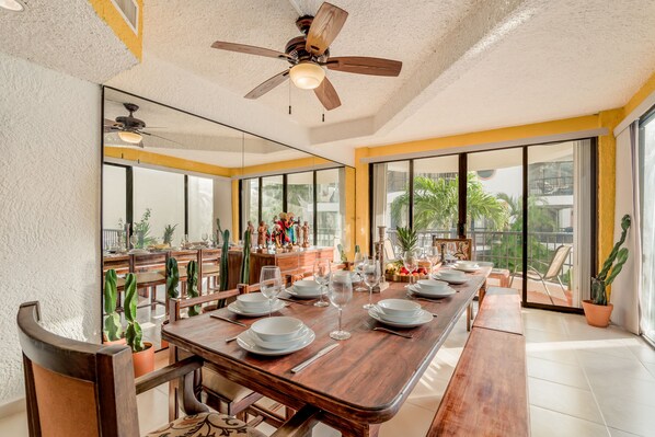 Enjoy meals in this dining area with a long table and views of the outdoors through large windows.