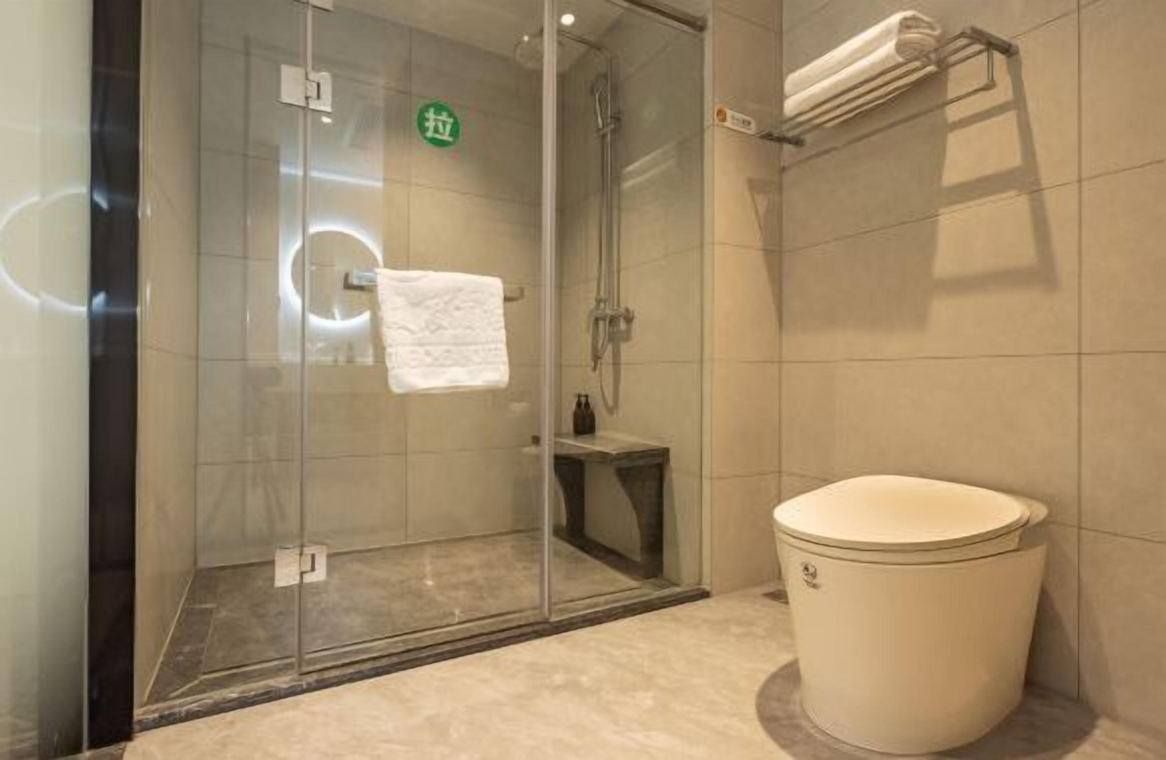 A glass-enclosed shower area with a toilet and a towel rack.