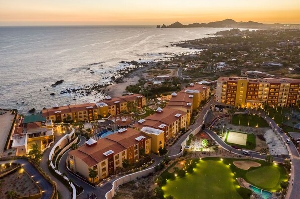 A resort with multiple buildings, a swimming pool, and a beach area.