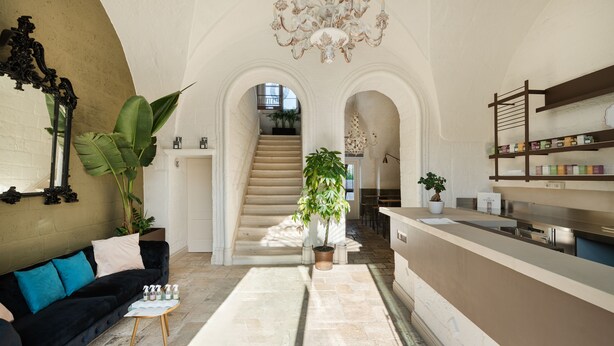 Un salón amplio con un sofá negro, una mesa de centro y una escalera que conduce a un nivel superior.