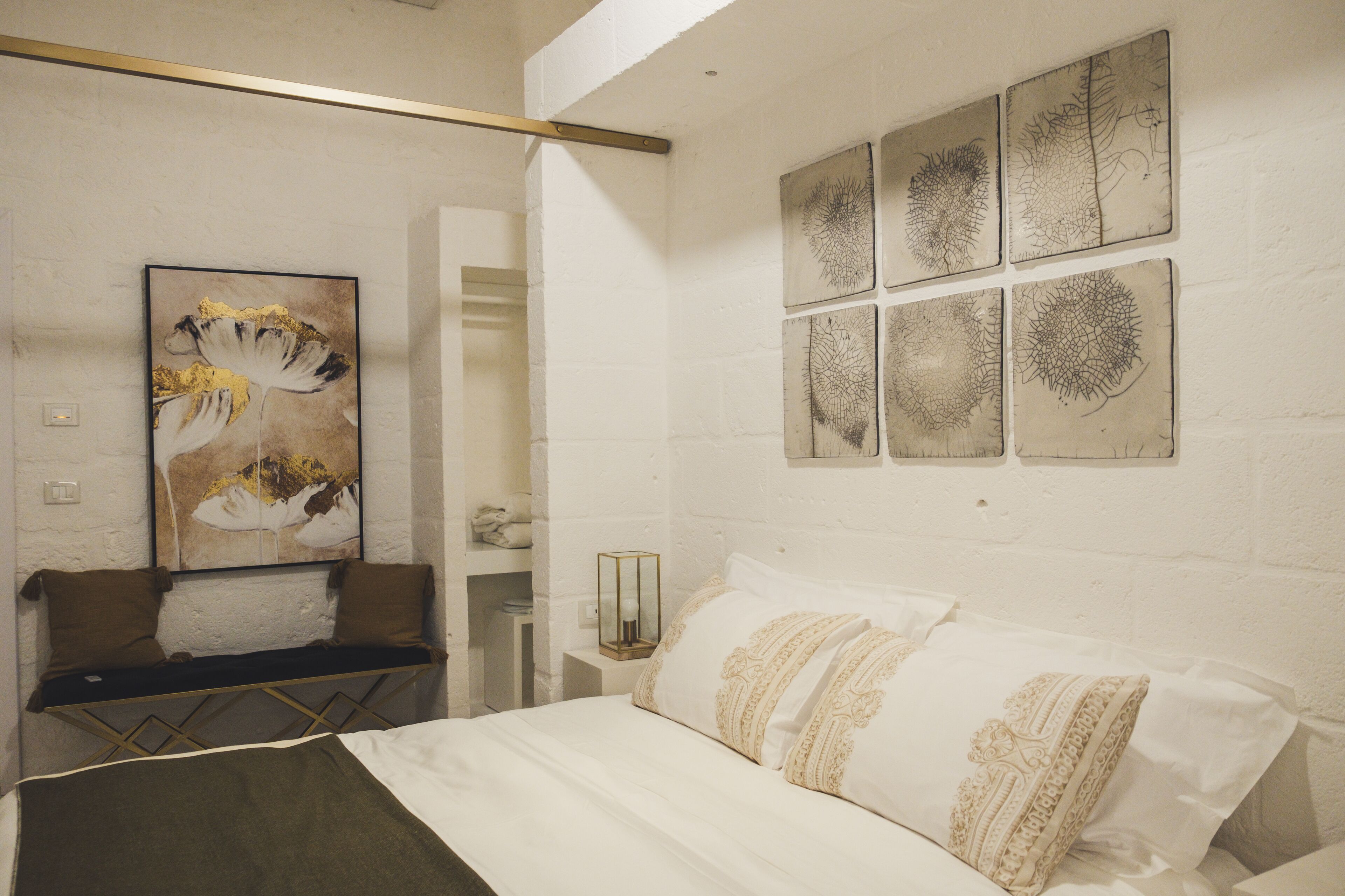 Una habitación de hotel con una cama, un banco y obras de arte en las paredes.