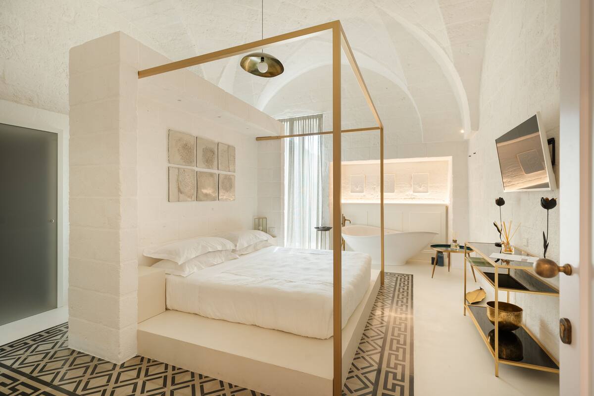 A modern bedroom with a four-poster bed, a built-in vanity, and a television mounted on the wall.