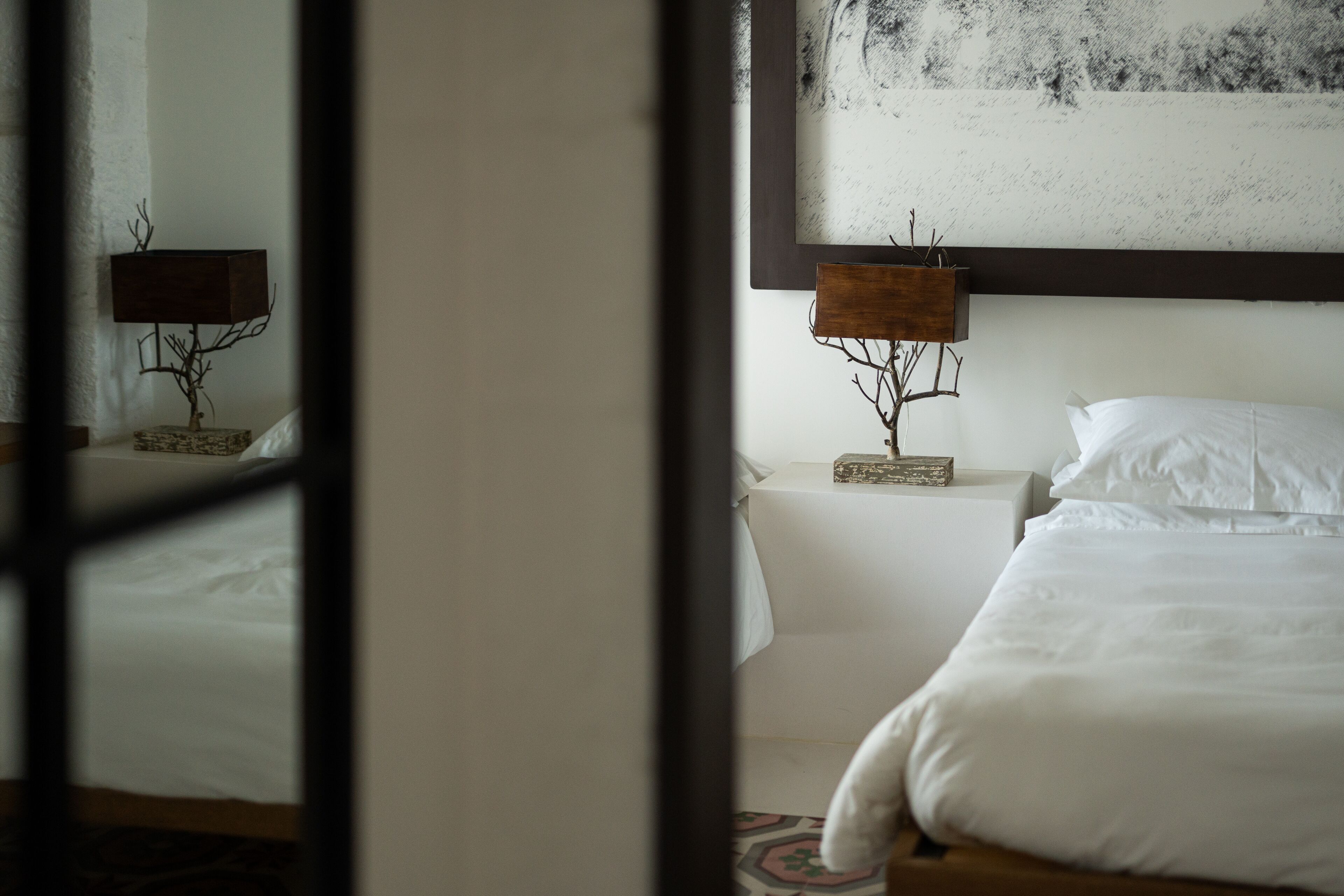 A hotel room with a bed, a nightstand with a lamp, and a painting on the wall.