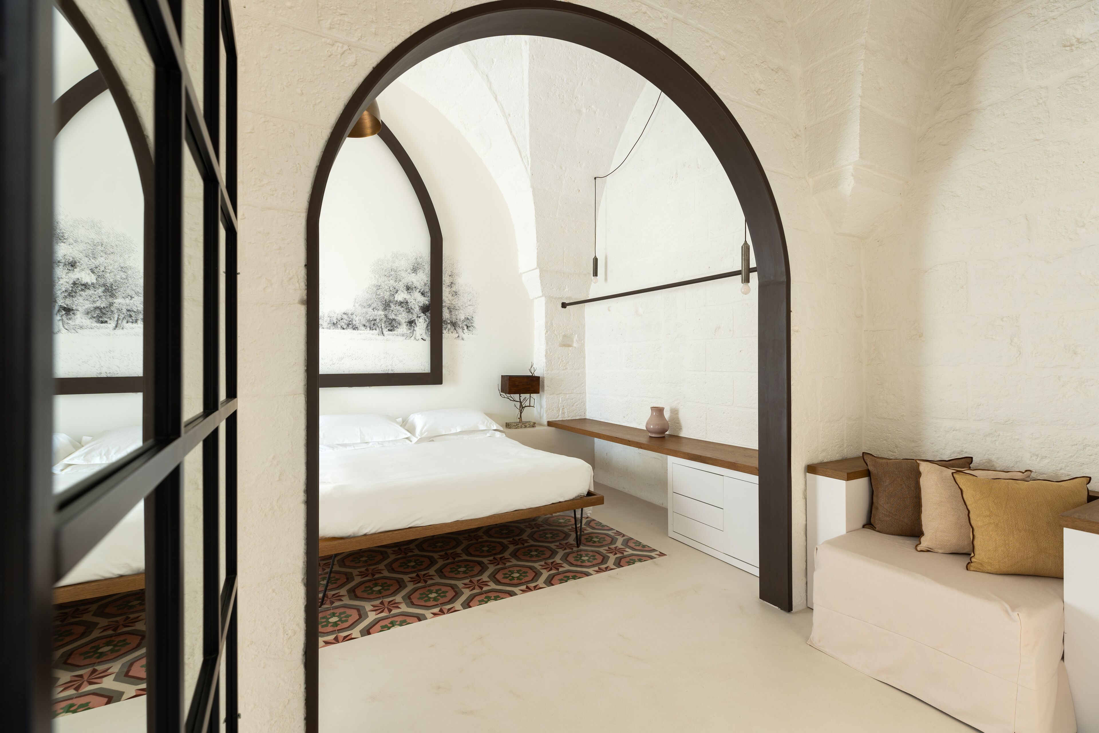 Un dormitorio con una cama, una mesita de noche, un aparador y un sofá.