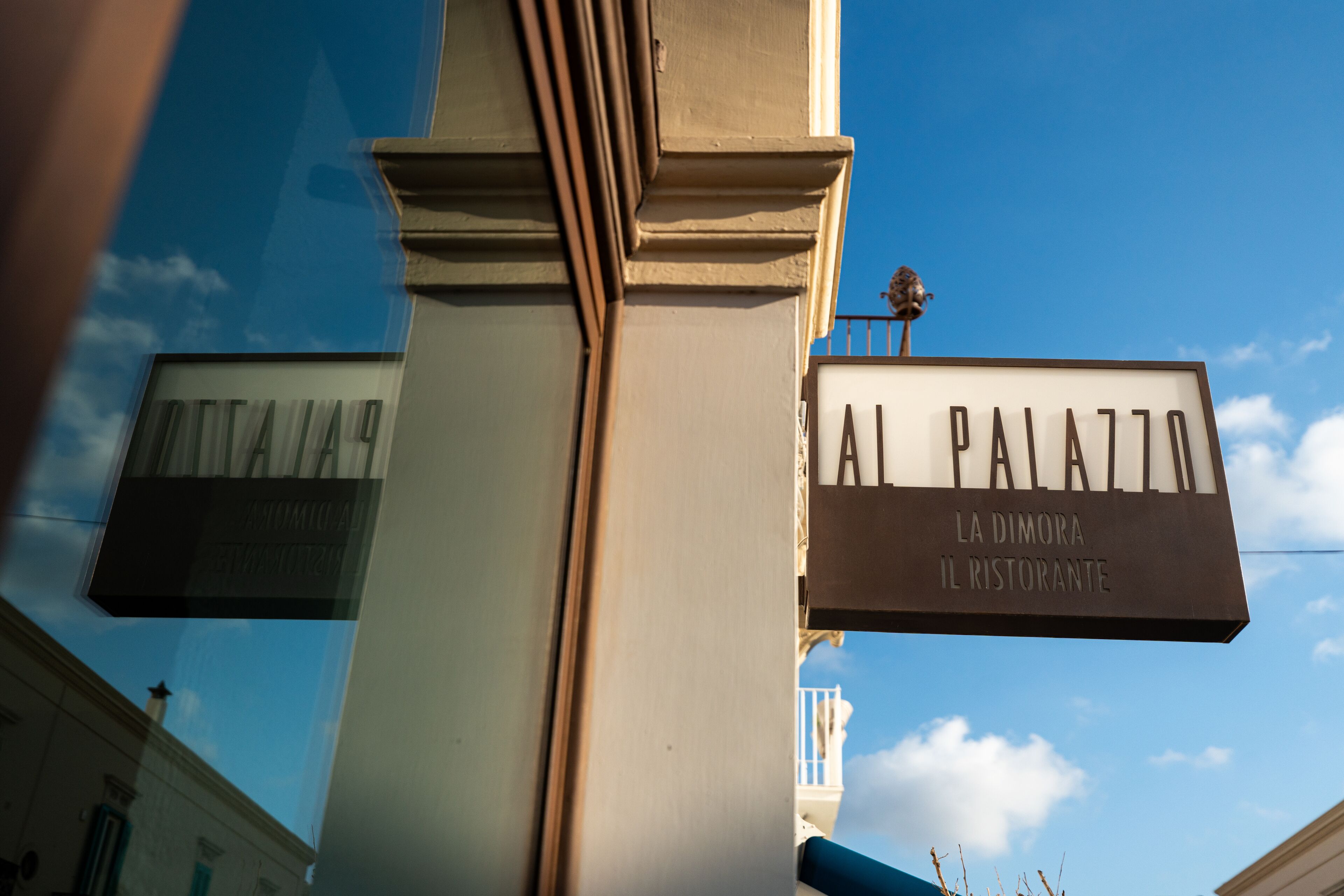 Una señal de calle con la palabra "PALAZZO" y "LA DIMORA IL RISTORANTE" que indica un restaurante.