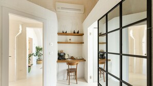 Una cocina con estantes de madera, una cafetera y una silla.